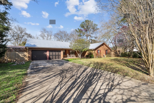 view of front of house with a front lawn, aphalt driveway, fence, metal roof, and a garage