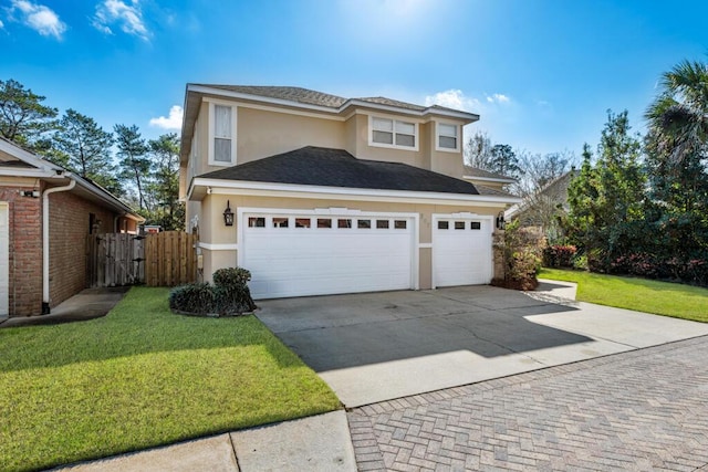 view of front of property featuring concrete driveway, fence, a front lawn, and stucco siding