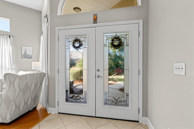 entrance foyer featuring light tile patterned floors, french doors, and baseboards