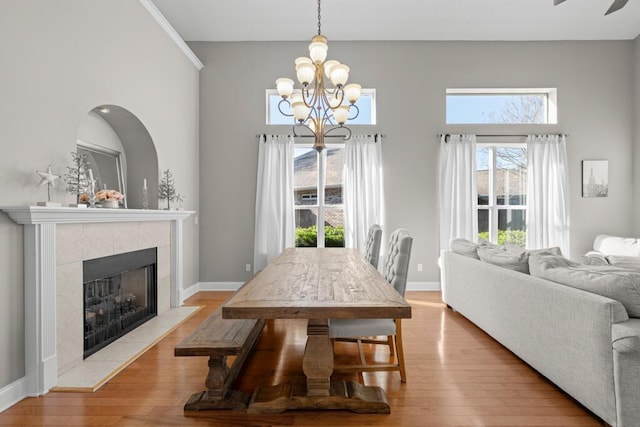 dining space with a chandelier, light wood-style flooring, a fireplace, and baseboards