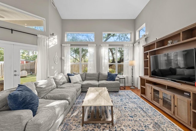 living room featuring a high ceiling, wood finished floors, visible vents, and french doors