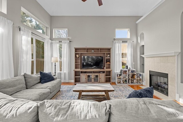 living room featuring a healthy amount of sunlight, a fireplace, baseboards, and ceiling fan