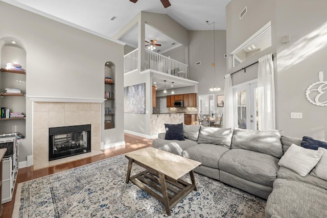 living area featuring a ceiling fan, wood finished floors, visible vents, a tile fireplace, and french doors