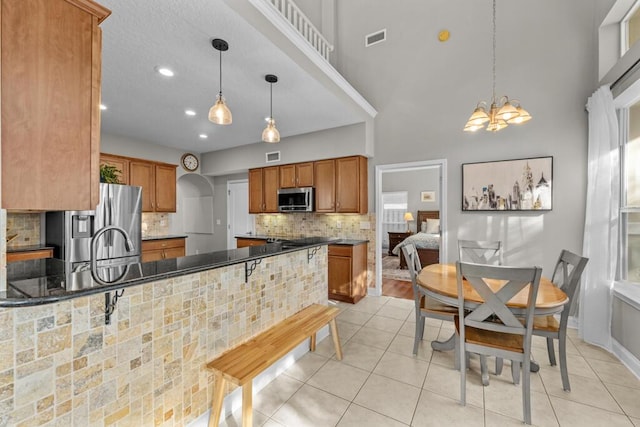 kitchen featuring dark countertops, visible vents, backsplash, brown cabinets, and stainless steel appliances