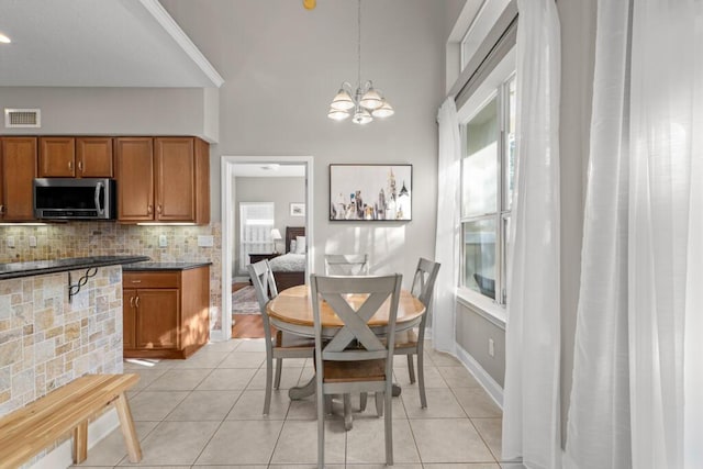 dining area with a notable chandelier, light tile patterned flooring, visible vents, and baseboards