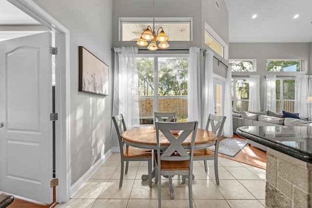 dining room featuring a notable chandelier, recessed lighting, a high ceiling, light tile patterned flooring, and baseboards