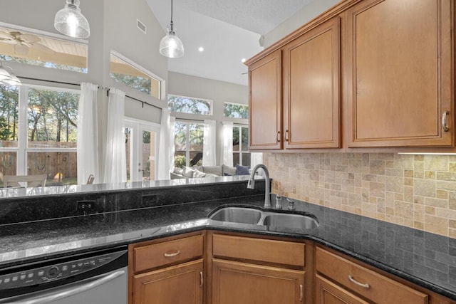 kitchen with brown cabinets, a sink, vaulted ceiling, stainless steel dishwasher, and tasteful backsplash