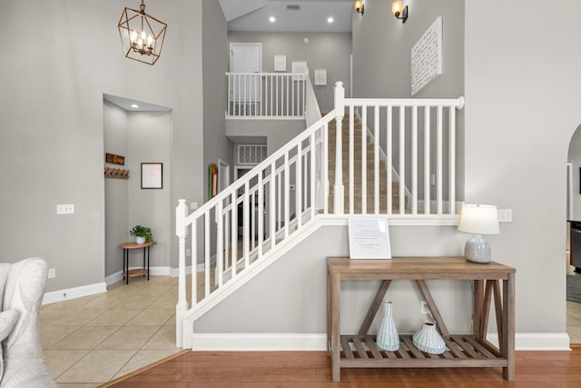 stairway with baseboards, a high ceiling, wood finished floors, and arched walkways