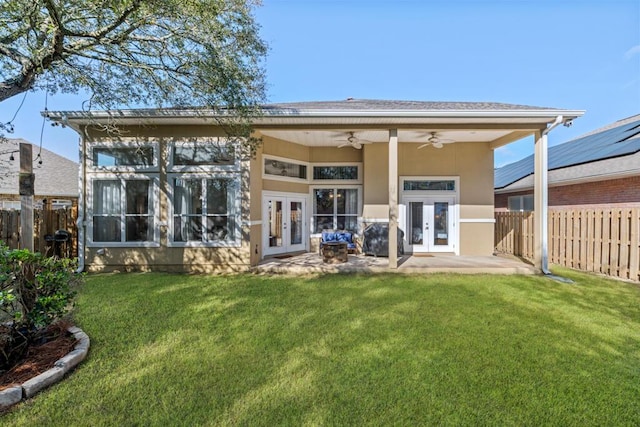 back of property featuring stucco siding, a lawn, a ceiling fan, a fenced backyard, and french doors