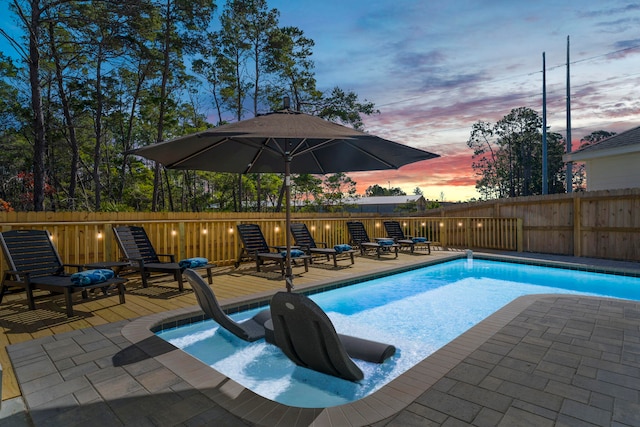 pool at dusk featuring a fenced in pool, a patio area, and fence