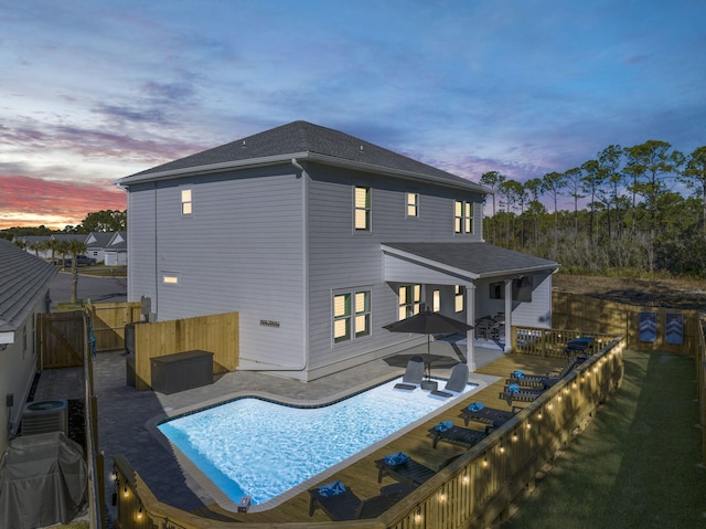 back of property at dusk with a gate, a patio, central AC, a fenced backyard, and a fenced in pool