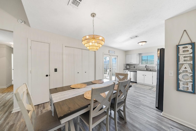 dining space with light wood-style floors, visible vents, french doors, and baseboards