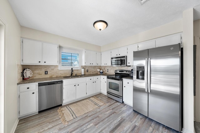 kitchen with light wood-style flooring, white cabinets, stainless steel appliances, and a sink