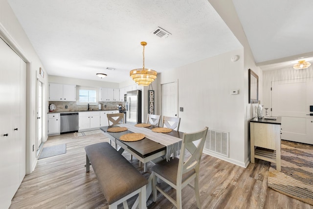 dining room featuring an inviting chandelier, visible vents, and light wood-type flooring