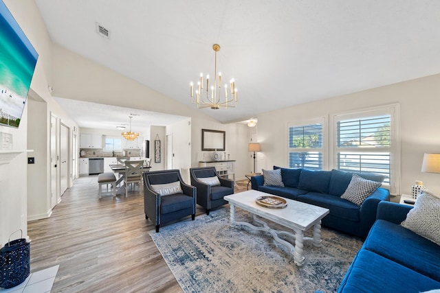 living area with lofted ceiling, a notable chandelier, a healthy amount of sunlight, and light wood-style floors