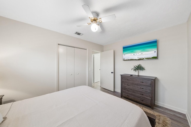 bedroom with visible vents, baseboards, wood finished floors, a closet, and a ceiling fan