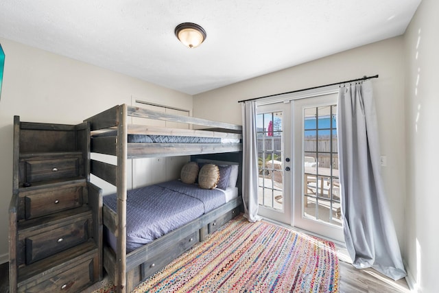 bedroom featuring access to exterior, french doors, and wood finished floors