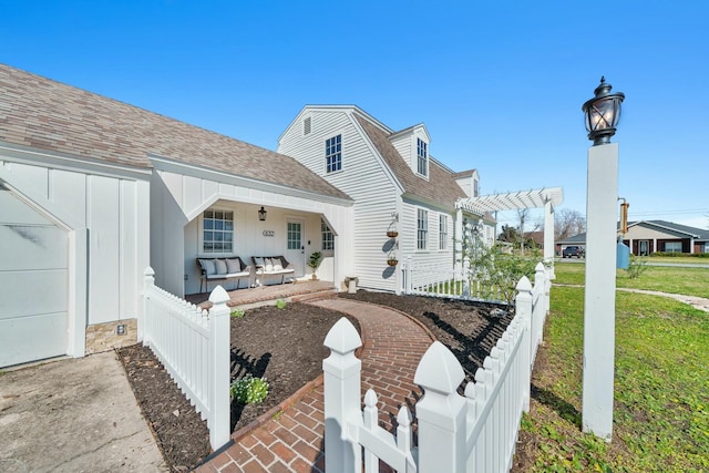 view of front facade with a pergola, board and batten siding, roof with shingles, covered porch, and fence private yard