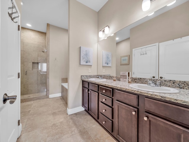 bathroom featuring double vanity, a shower stall, baseboards, and a sink