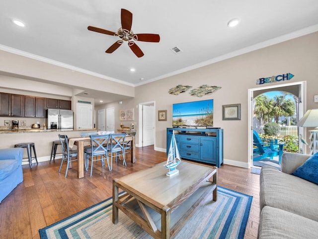 living area with crown molding, baseboards, and hardwood / wood-style floors