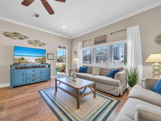 living room with light wood-type flooring, visible vents, a ceiling fan, crown molding, and baseboards