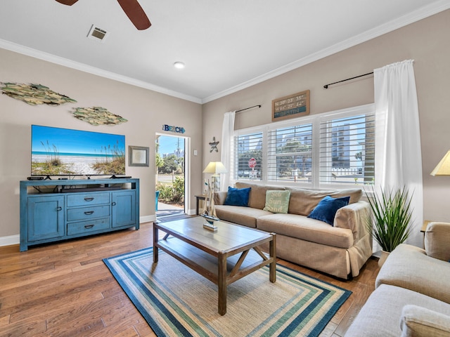 living room featuring visible vents, ceiling fan, baseboards, ornamental molding, and light wood-style floors