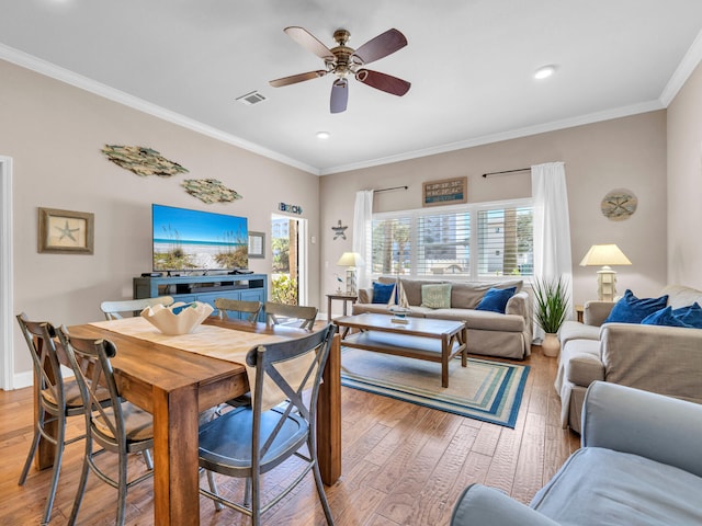 dining area featuring light wood finished floors, visible vents, a ceiling fan, and ornamental molding