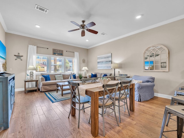 dining room featuring crown molding, light wood-style flooring, and visible vents