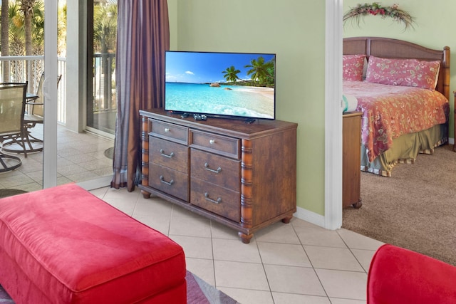 bedroom featuring light tile patterned floors, baseboards, light colored carpet, and access to exterior