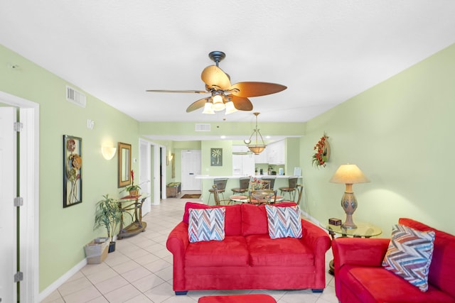 living room with light tile patterned floors, visible vents, baseboards, and ceiling fan