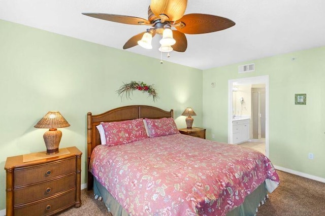 carpeted bedroom with ensuite bath, baseboards, visible vents, and ceiling fan