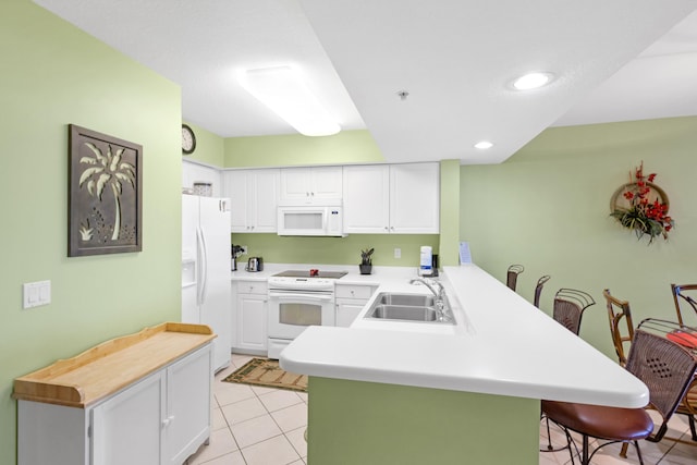 kitchen featuring a kitchen breakfast bar, a peninsula, white cabinets, white appliances, and a sink