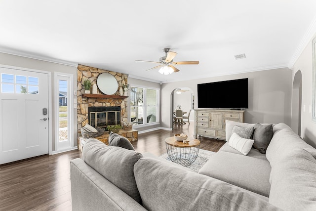 living area with dark wood-type flooring, crown molding, and arched walkways