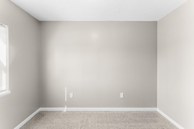 carpeted spare room with a textured ceiling and baseboards