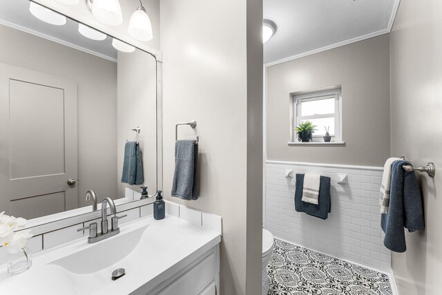 half bathroom with crown molding, toilet, tile walls, and wainscoting