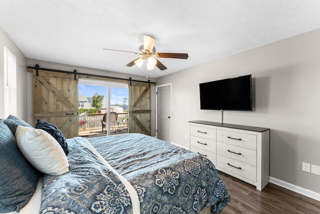 bedroom with baseboards, dark wood finished floors, a barn door, a textured ceiling, and access to outside