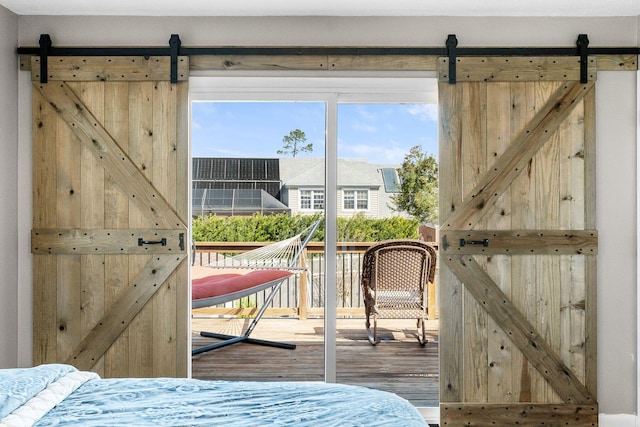 unfurnished bedroom with access to exterior, a barn door, and wood finished floors