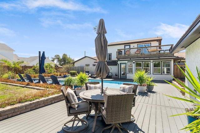 wooden terrace with outdoor dining area, a fenced backyard, and a fenced in pool