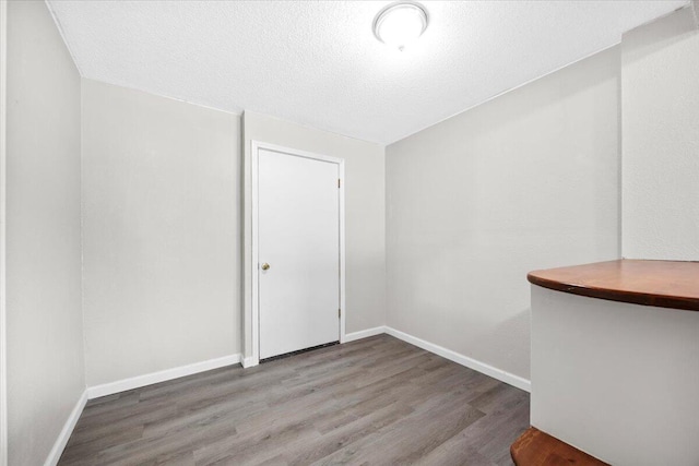 unfurnished room featuring wood finished floors, baseboards, and a textured ceiling