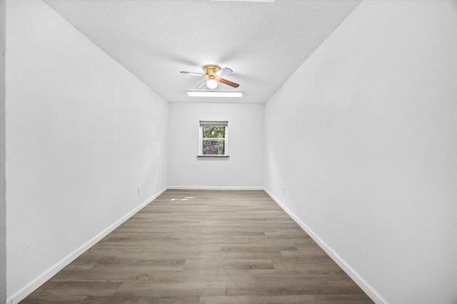 spare room with baseboards, a textured ceiling, ceiling fan, and wood finished floors