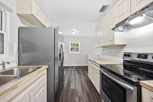 kitchen featuring visible vents, under cabinet range hood, tasteful backsplash, dark wood-style floors, and appliances with stainless steel finishes