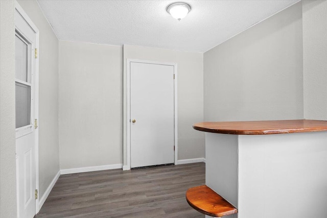 dining space featuring a textured ceiling, baseboards, and wood finished floors