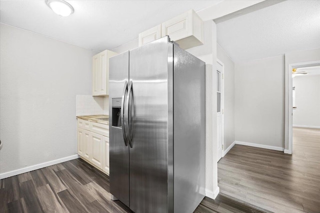 kitchen with dark wood-style floors, baseboards, light countertops, stainless steel fridge, and backsplash