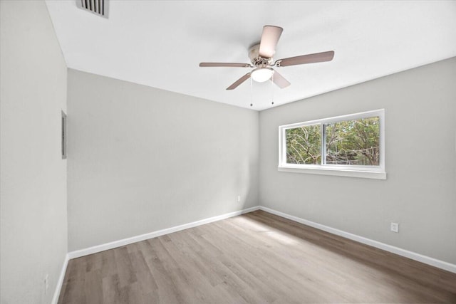 empty room with a ceiling fan, wood finished floors, baseboards, and visible vents