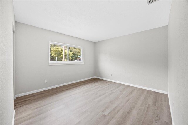 empty room with baseboards and wood finished floors