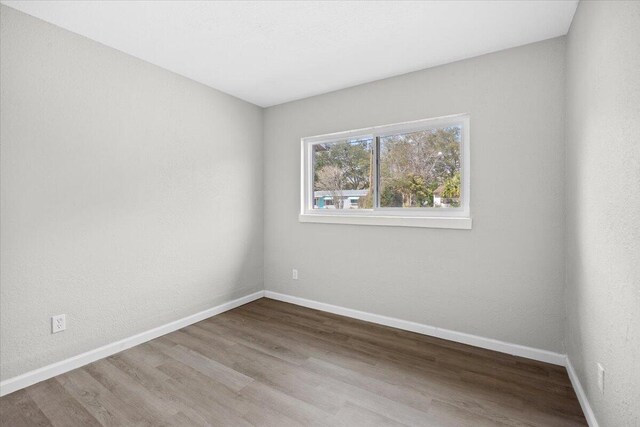 spare room with wood finished floors and baseboards