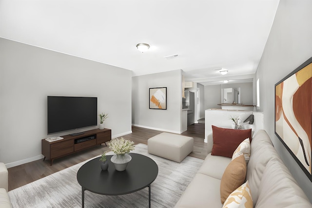 living area featuring visible vents, baseboards, and wood finished floors