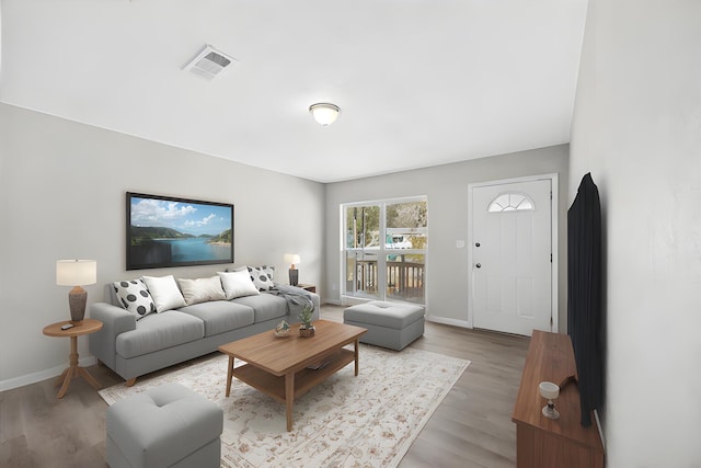 living room featuring visible vents, light wood-style flooring, and baseboards