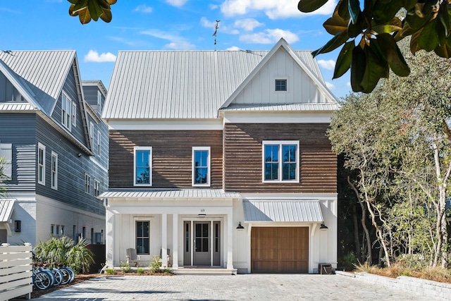 view of front of home with driveway, covered porch, board and batten siding, an attached garage, and metal roof