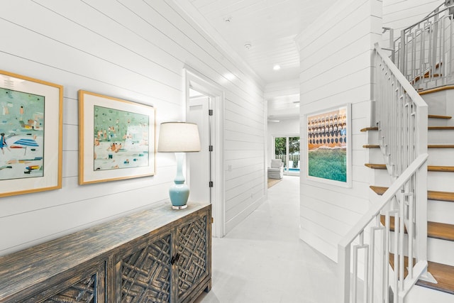 hallway featuring wooden walls, recessed lighting, and stairs